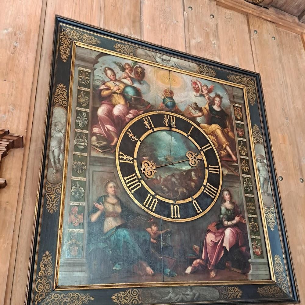 A large ornate clock face with Roman numerals and a painted scene.